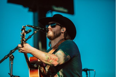 A singer singing into a microphone with a guitar